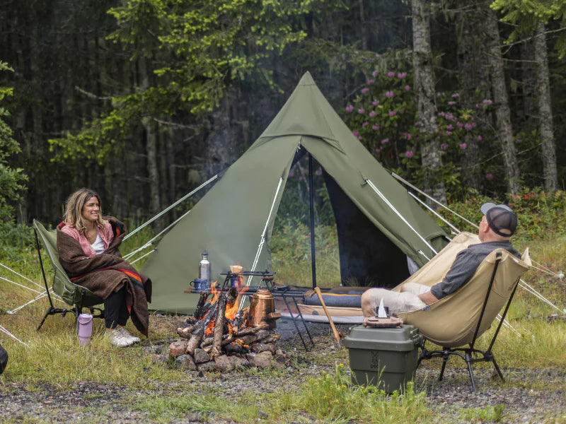 Man and woman camping by a fire.