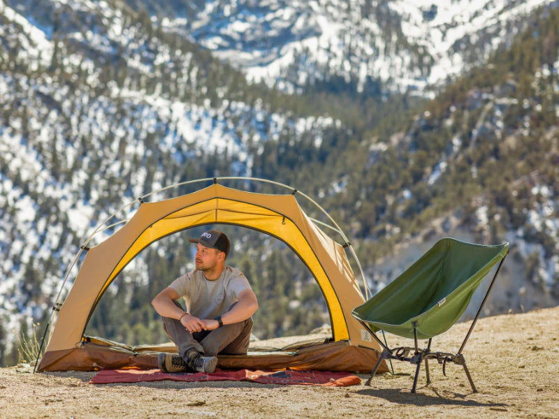 Man sitting by a tent and green chair
